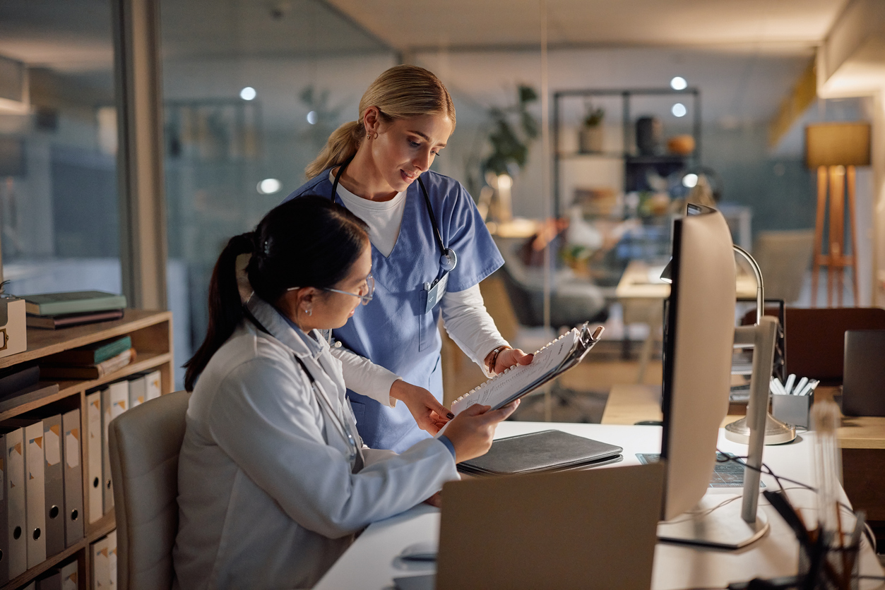 A nurse reviews patient information with a doctor.