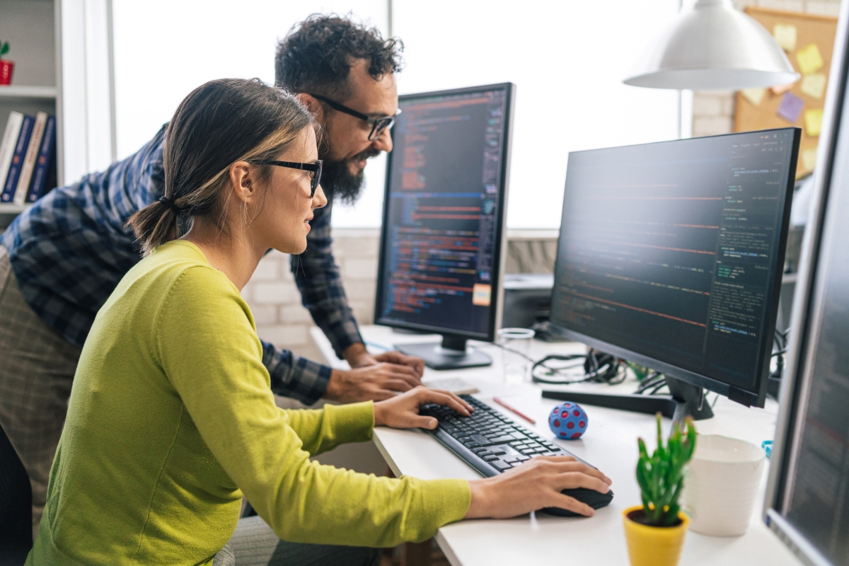 Professionals in a business environment working on monitors.