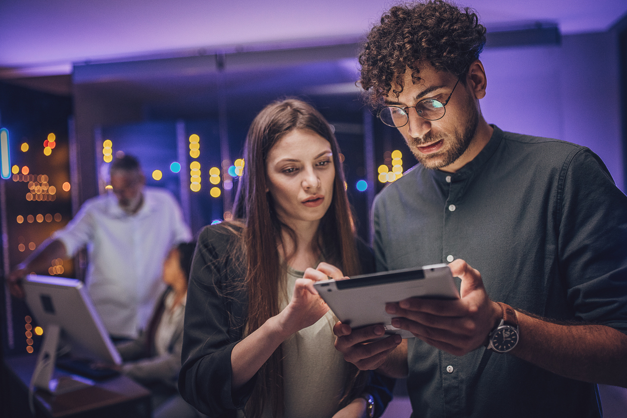 A Cybersecurity Architect and an Engineer Look at a Tablet While Standing in a Server Room.
