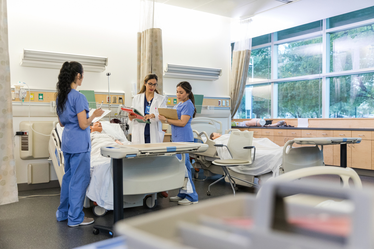 A nurse preceptor stands with a nurse in a medical facility.