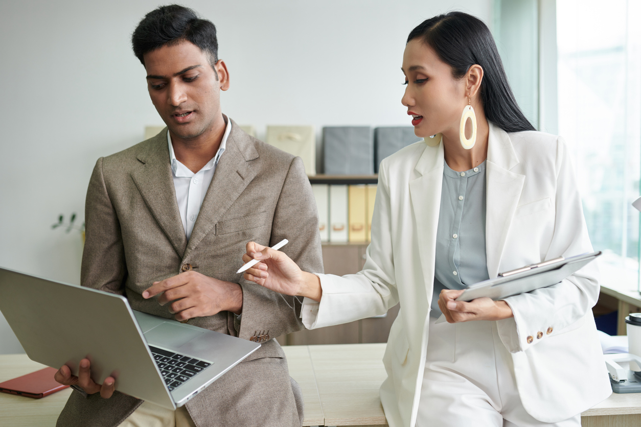 Cybersecurity Professionals Talking in an Office and Looking at a Laptop.