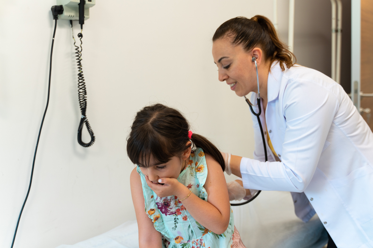 A family nurse practitioner listens to a patient’s cough through a stethoscope. 