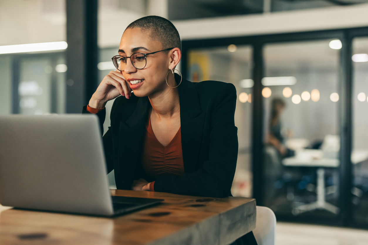 A Cybersecurity Professional Sitting at a Desk Looking at a Laptop in an Office.