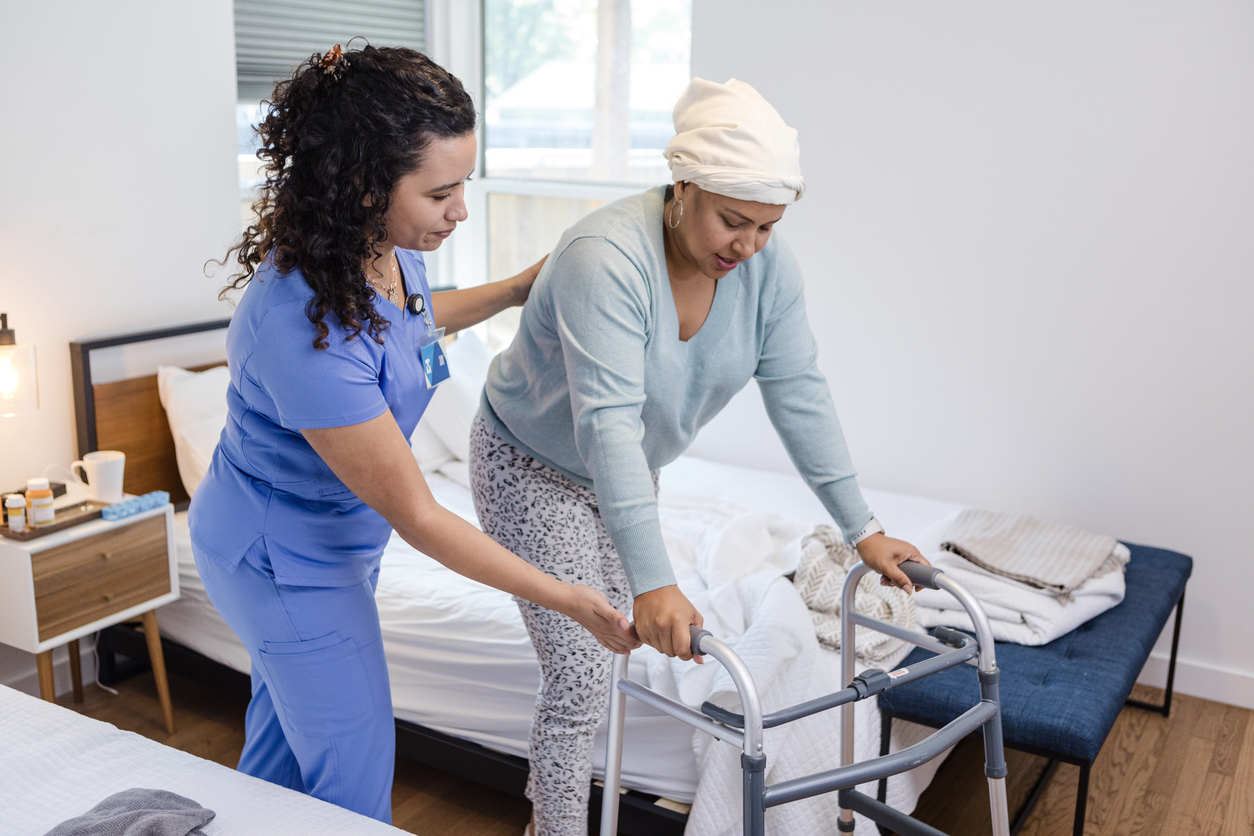 A palliative care nurse helps a patient with her walker.