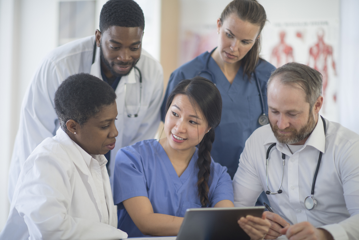 Nurses and doctors sitting together in a medical facility with a tablet.