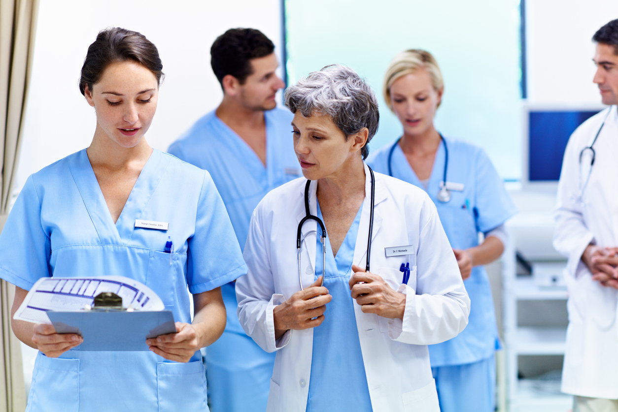 A charge nurse talking to a health care professional in a medical facility.