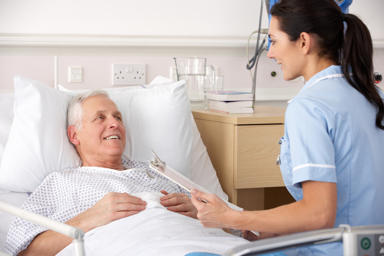 Bedside nurse sitting with a patient in a medical facility.