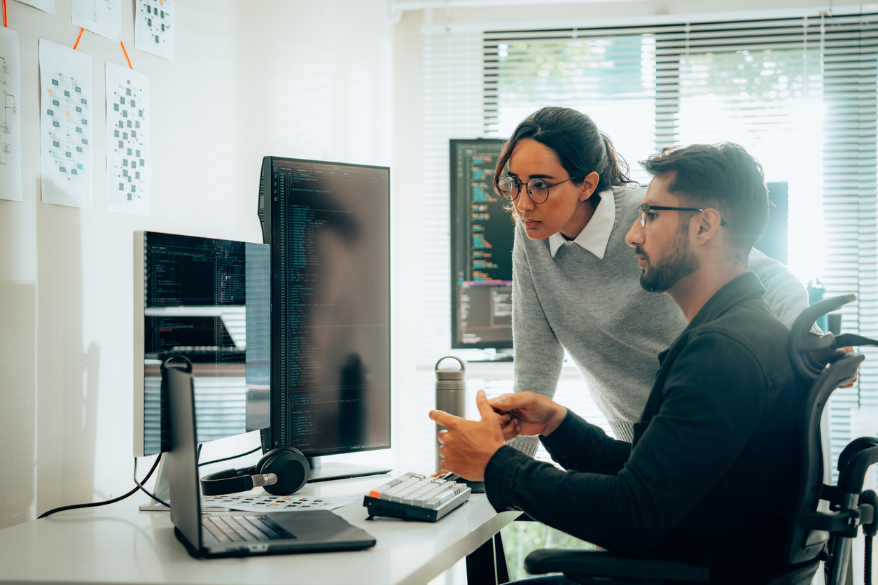 Two cybersecurity professionals looking at computer monitors.