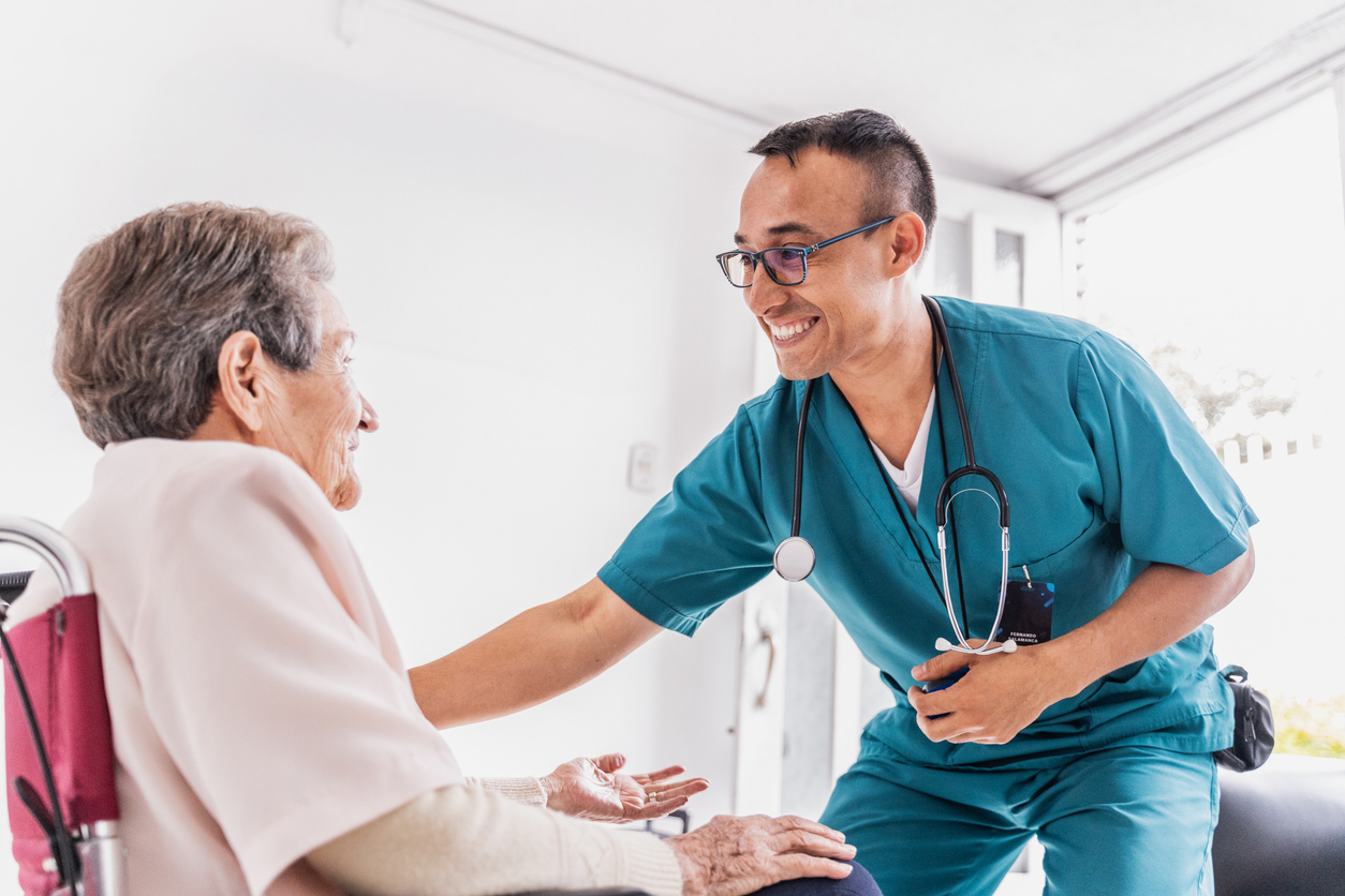 A nurse greets a patient in a wheelchair at an assisted living facility.