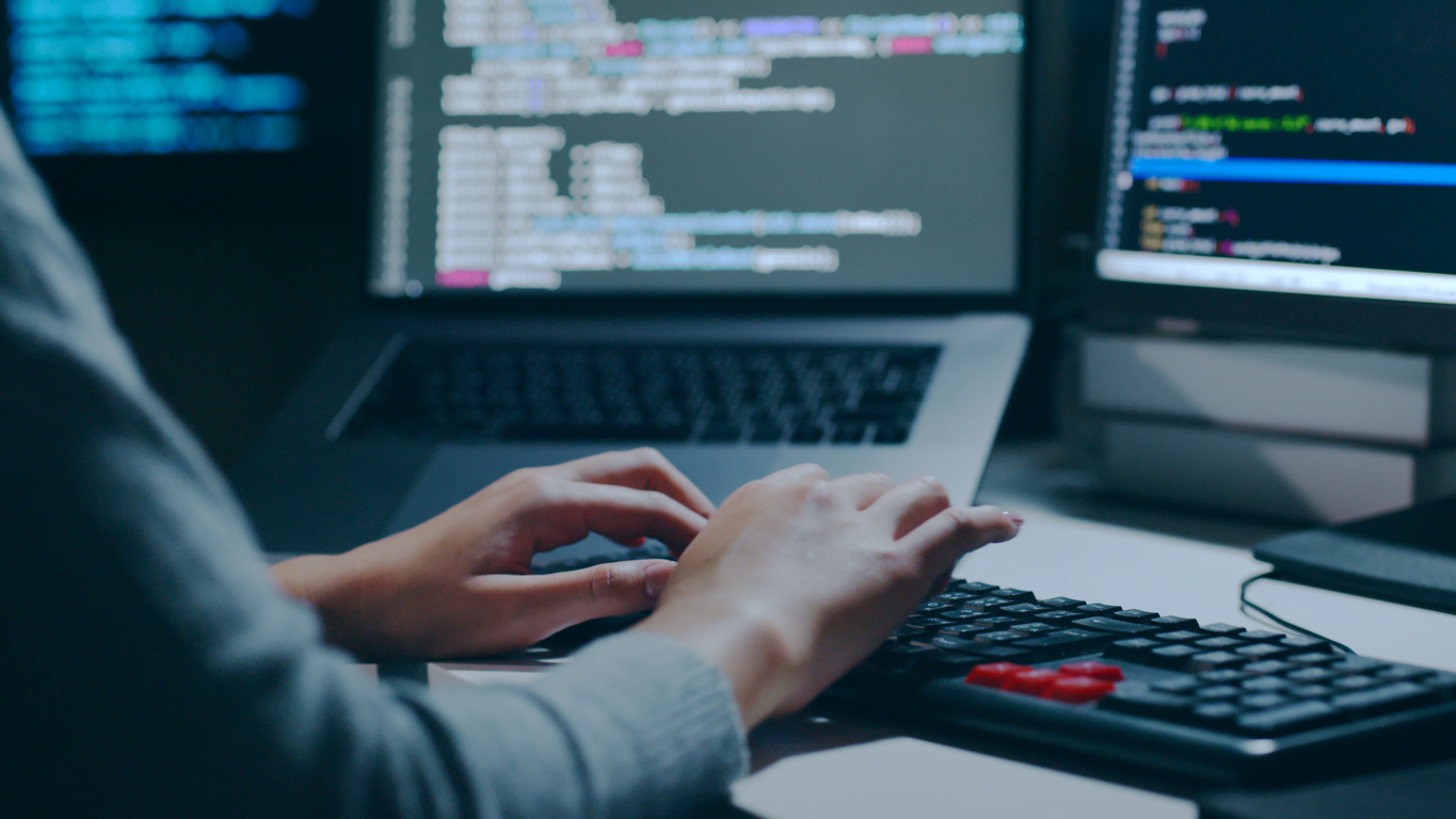 Close up of a Cybersecurity Attacker Working on Multiple Computers.