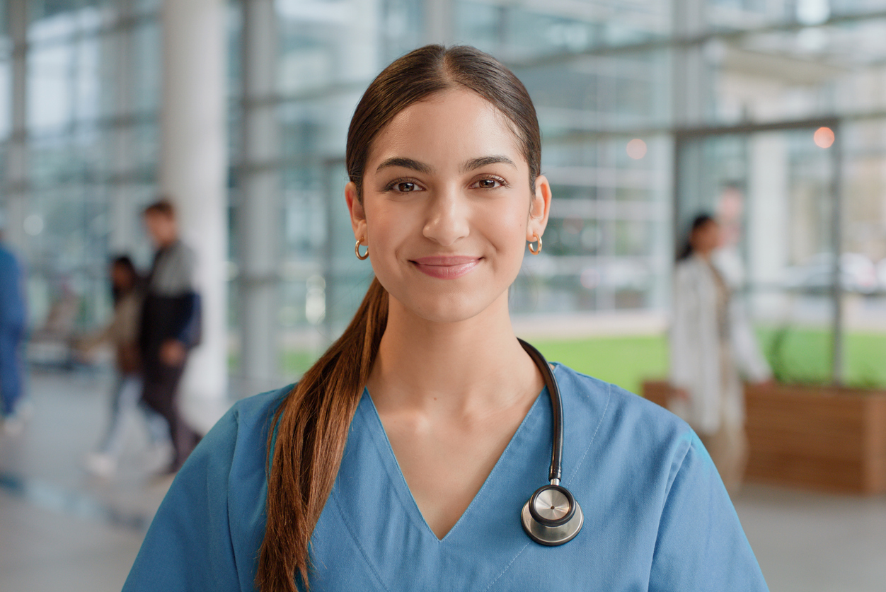 A smiling nurse standing in a hospital corridor.