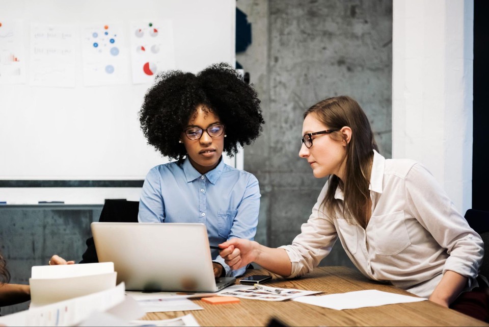 Stock photo of colleagues working together while looking over a computer.