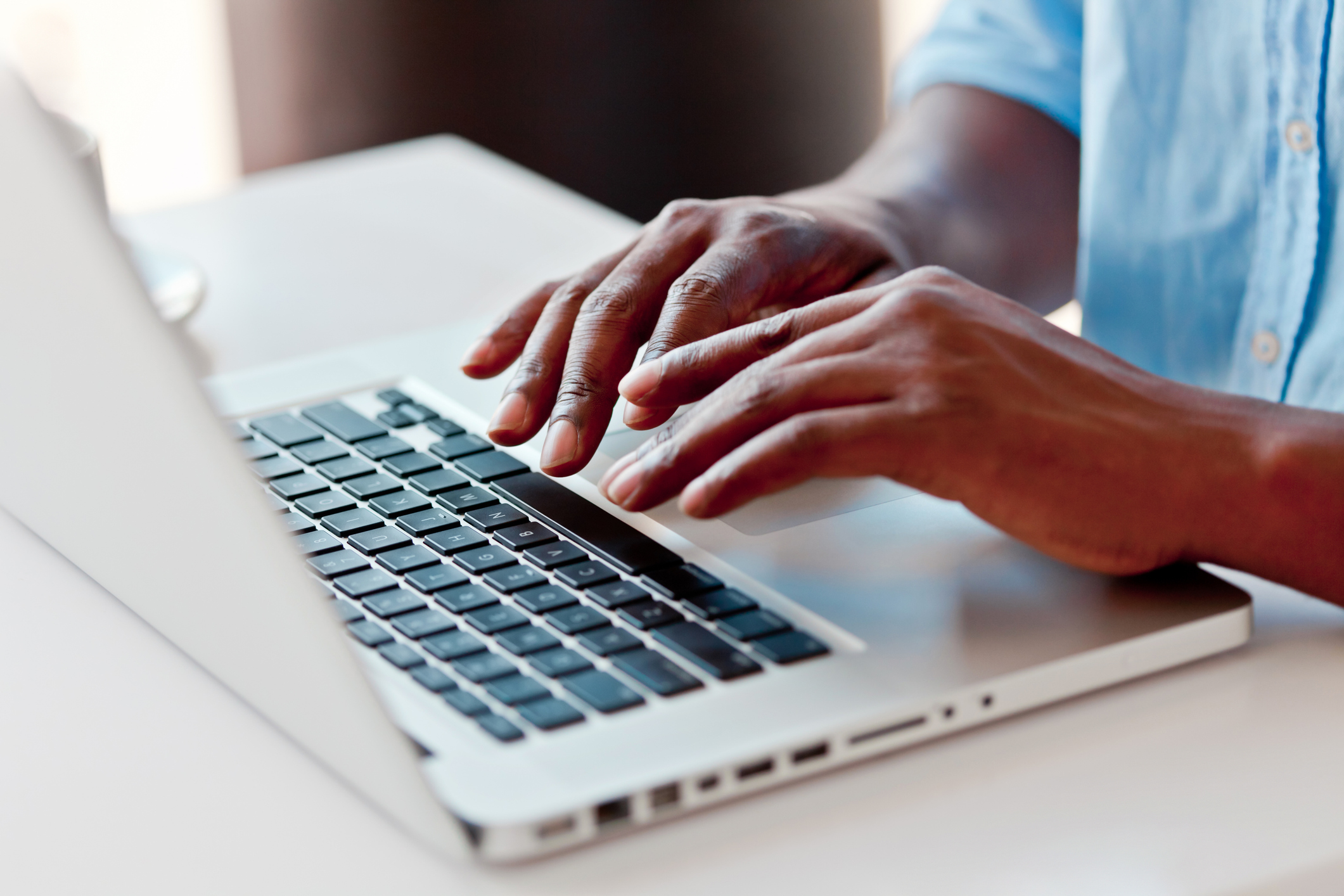 Hands type on a laptop keyboard.
