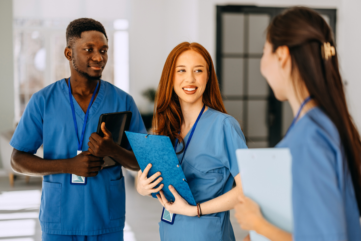 Three Nurses Wearing Scrubs and Talking in a Hospital Corridor..jpg